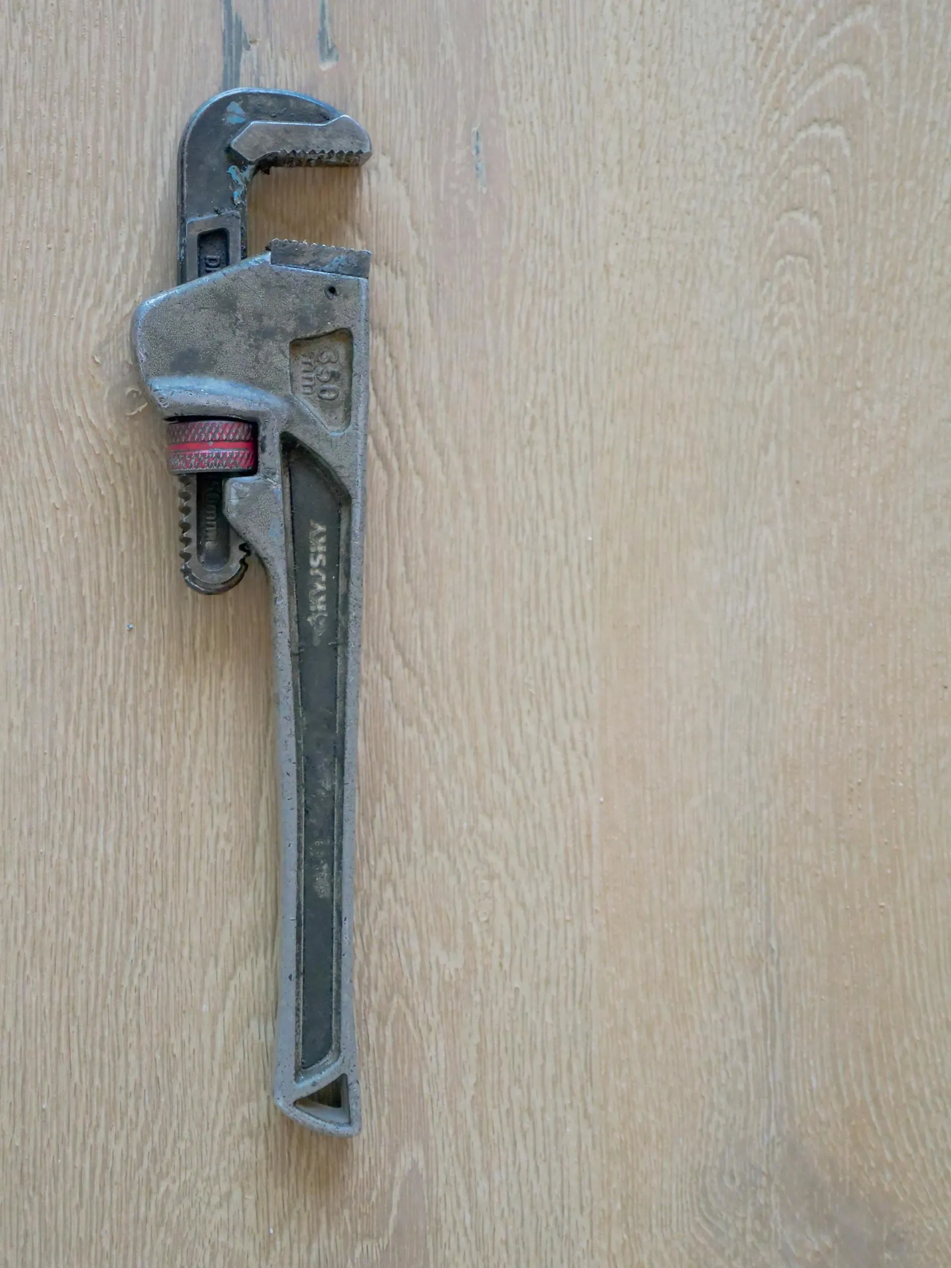 A pipe wrench resting on a wooden floor in an Exeter property